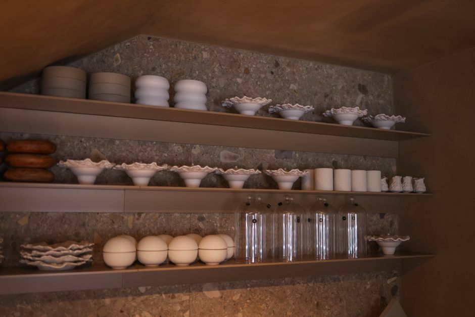 Stylish kitchen shelves display white ceramic dishes and glassware in a modern interior.