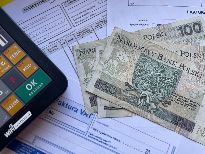 Polish currency placed on invoices with a calculator, illustrating financial transactions or budgeting.